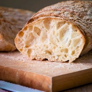 Ciabatta bread with open crumb on a cutting board.