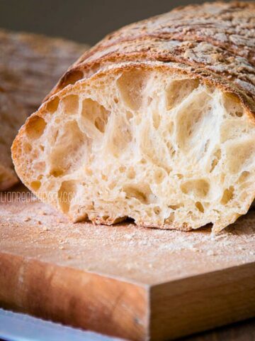 Ciabatta bread with open crumb on a cutting board.