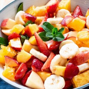 Italian fruit salad in a bowl garnished with mint leaves.