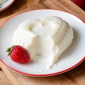 Panna cotta on a dessert plate with a strawberry on the side.