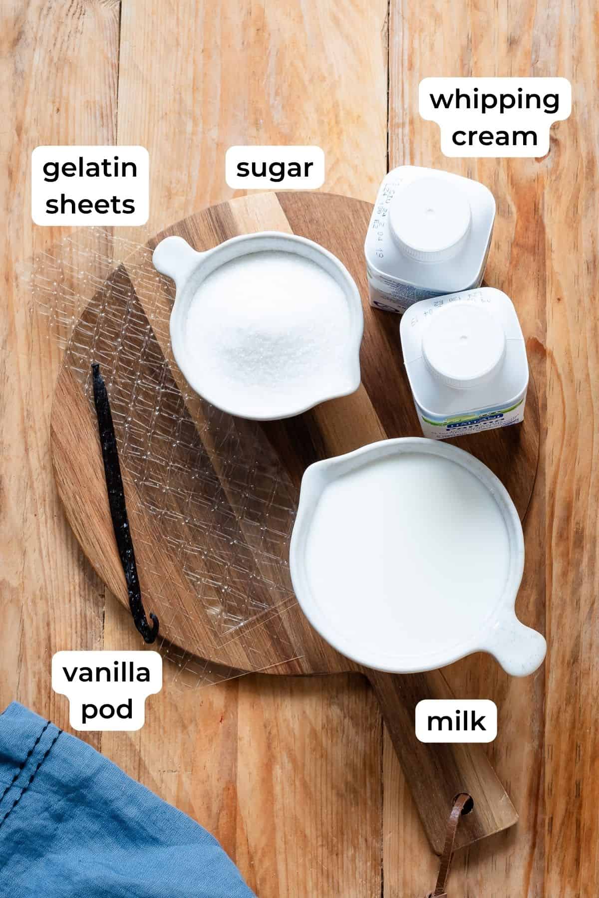 Ingredients needed to make panna cotta laid on a wooden surface.