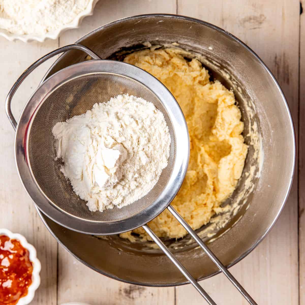 Adding sifted flour to the cookie batter.