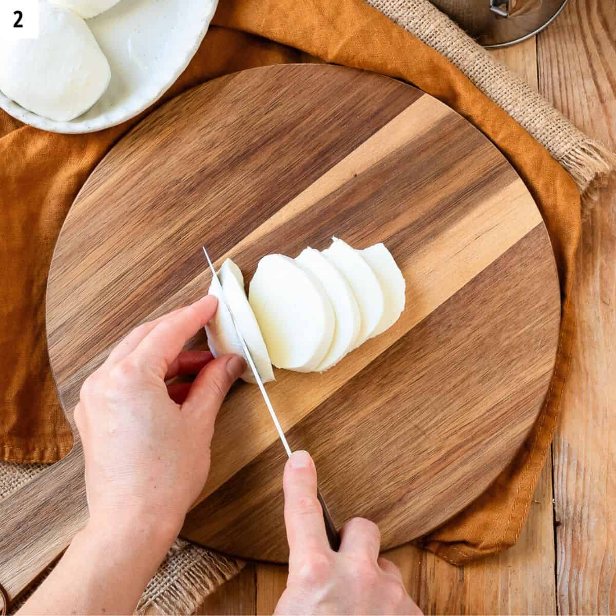 Cutting fresh mozzarella ball into slices.