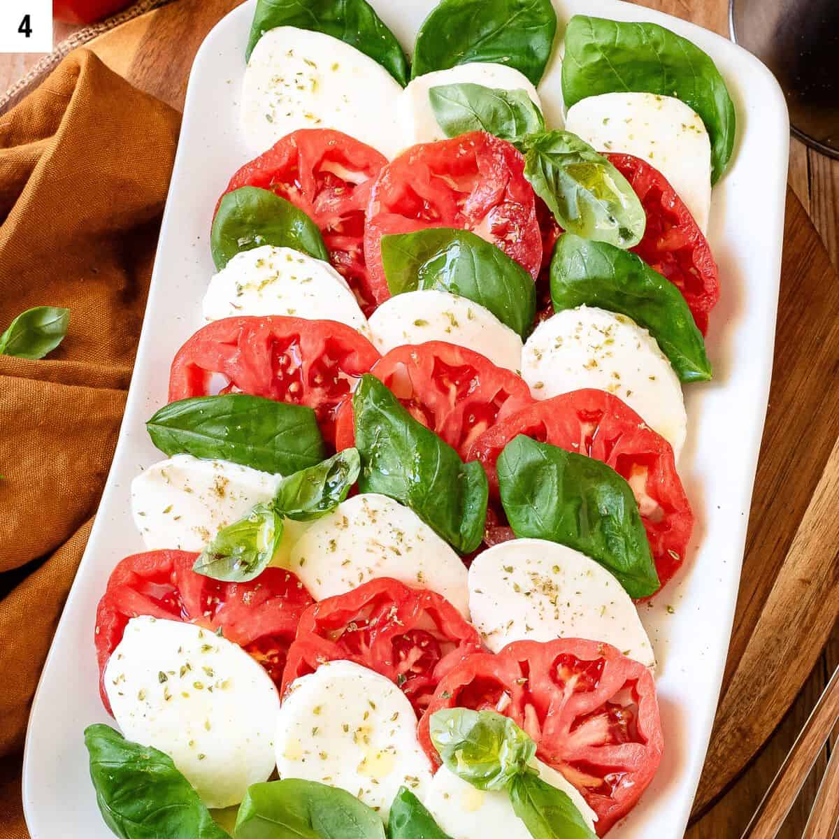 Tomatoe, mozzarella slices arranged on a servings plate alternated with basil leaves.