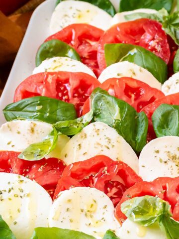 Caprese Salad sprinkled with oregano and olive oil on served on a white plate.