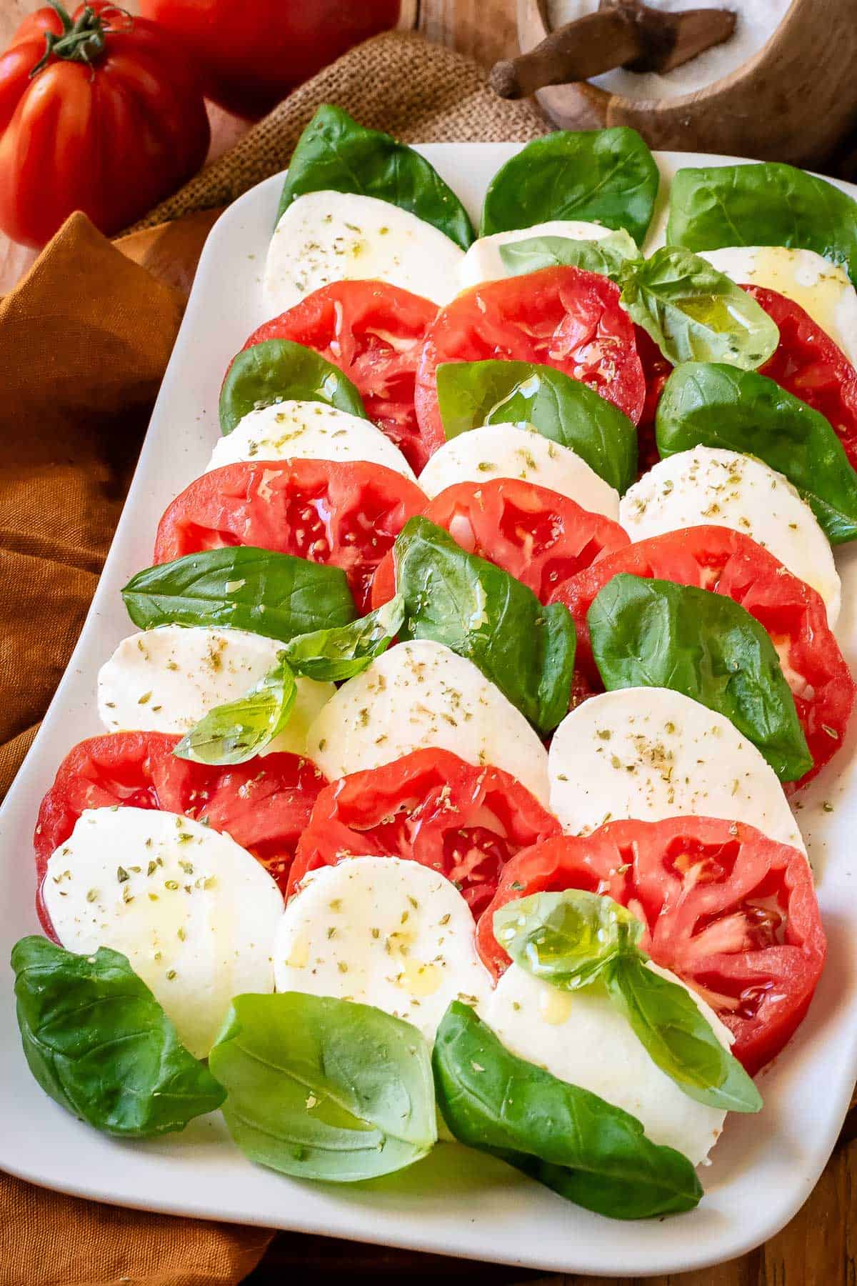 Tomato, basil and mozzarella layered on a serving plate.