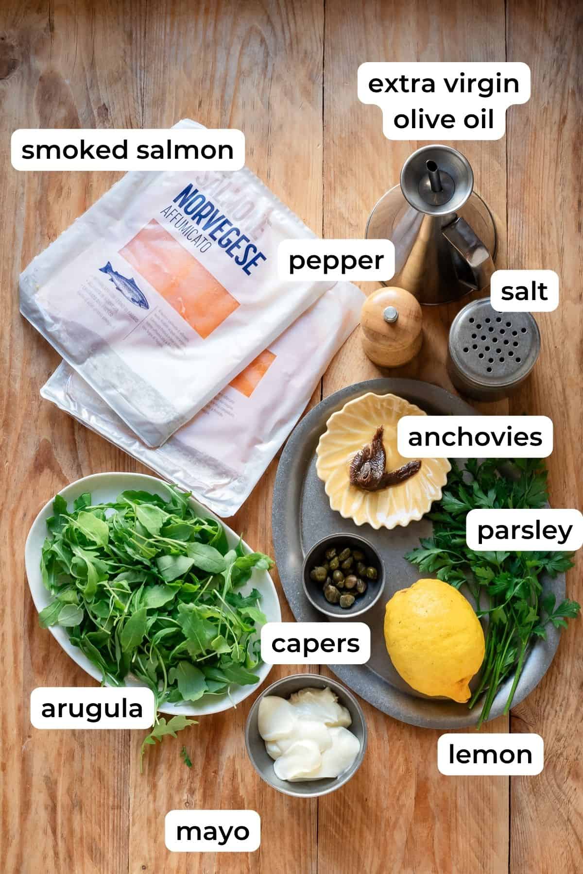 Ingredients needed for salmon carpaccio laid on a wooden background.