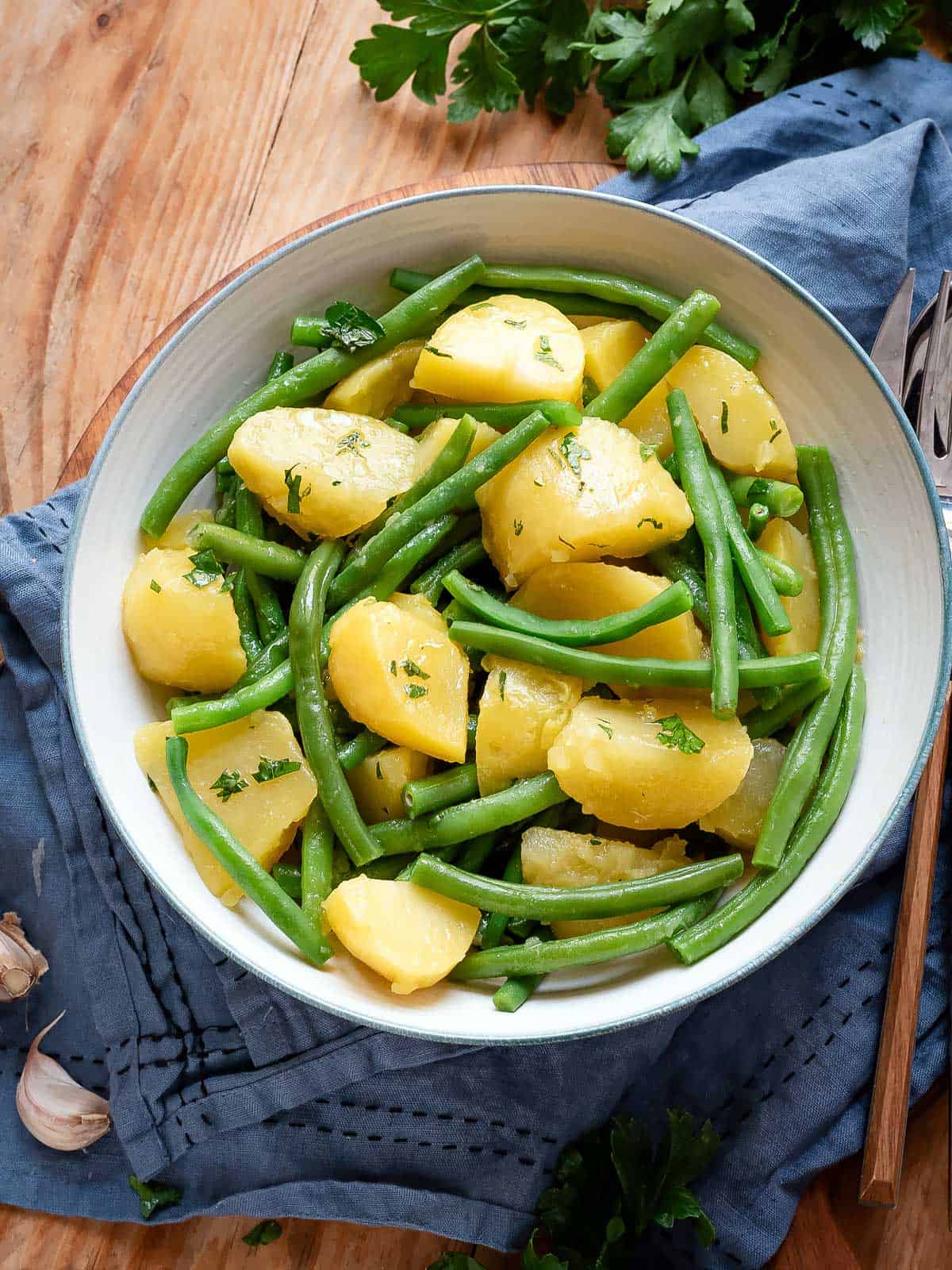 Green beans and creamy potatoes in a white bowl with a blue rim.