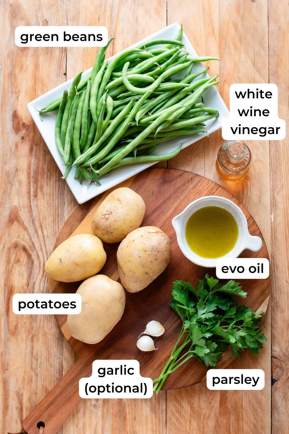 Ingredients needed to make potatoes and green beans laid on a wooden surface.