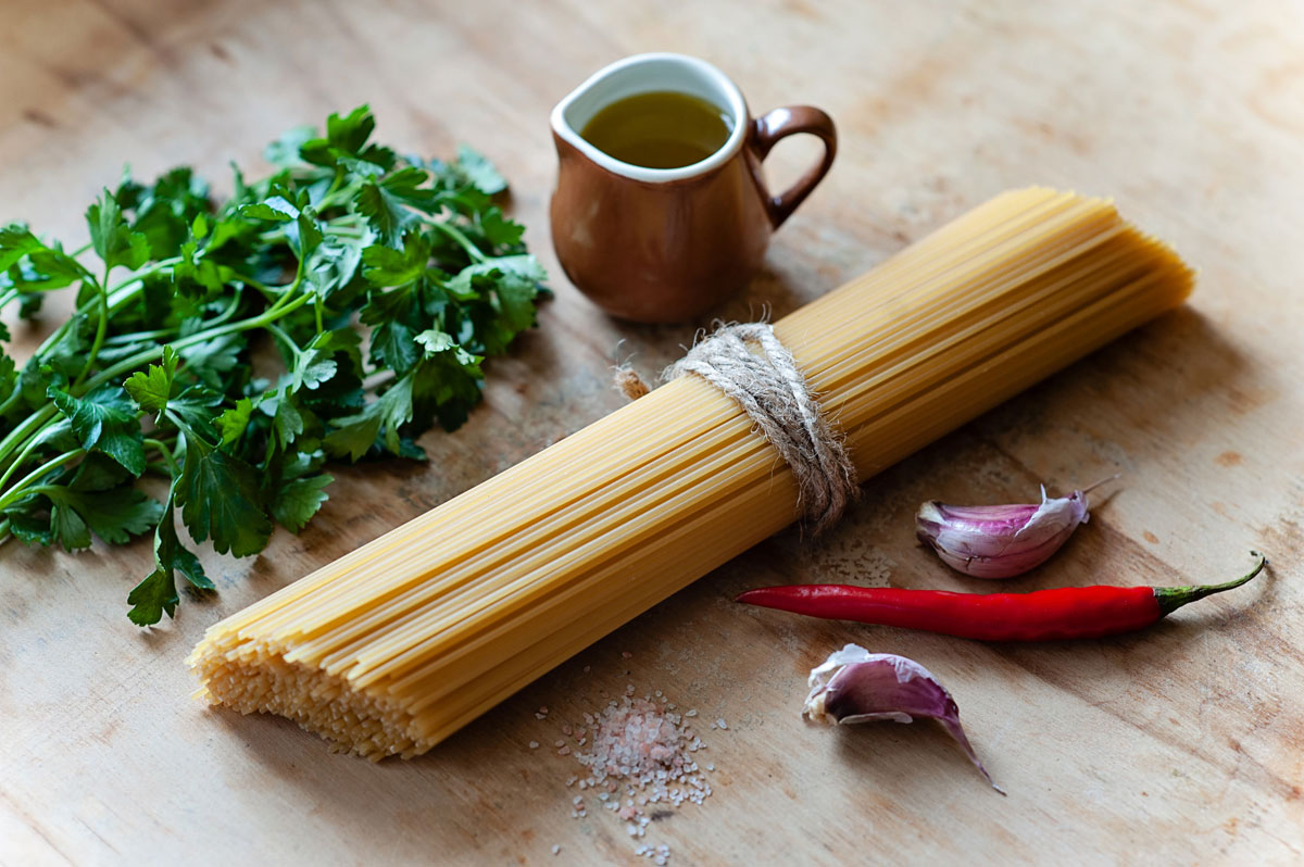 Ingredients needed for Spaghetti aglio e olio laid on a wooden surface.