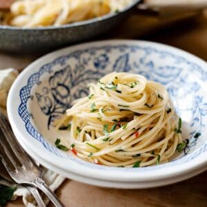 Spaghetti aglio e olio in a bowl with a fork on the side.