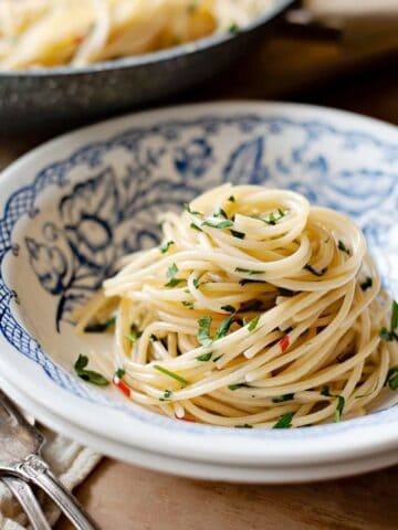 Spaghetti aglio e olio in a bowl with a fork on the side.