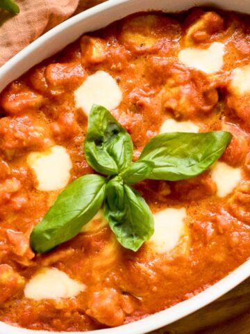 Chicken Sorrentino in a casserole garnished with basil leaves.