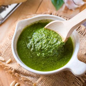 Creamy basil pesto scooped with a wooden spoon.