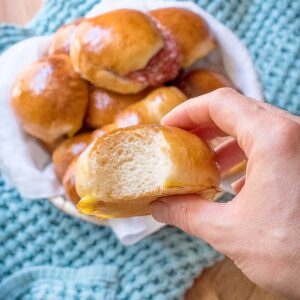 Milk bread roll in hand with more milk rolls in the background.