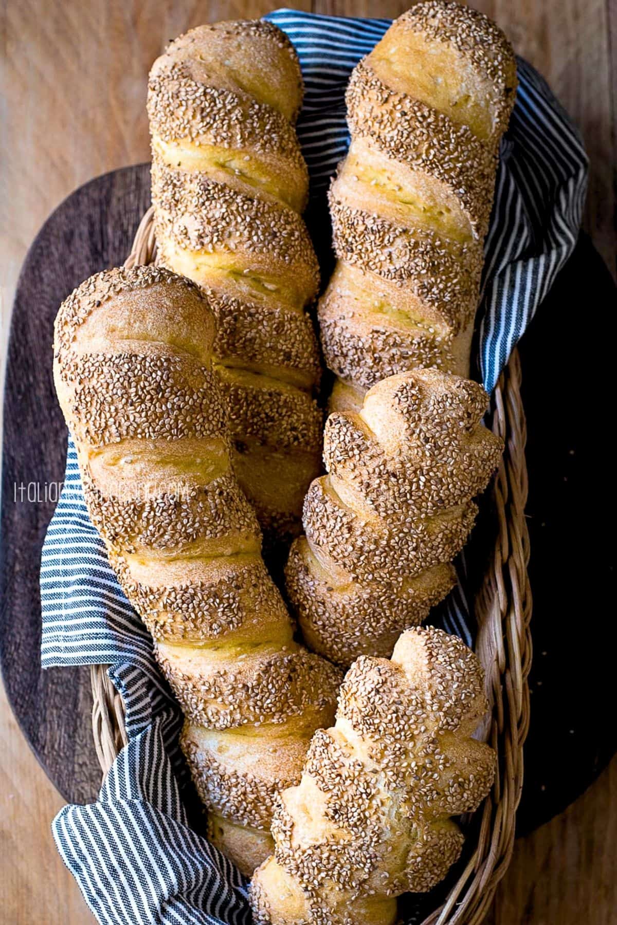 Semolina bread loaves in a basket on a wooden surface.