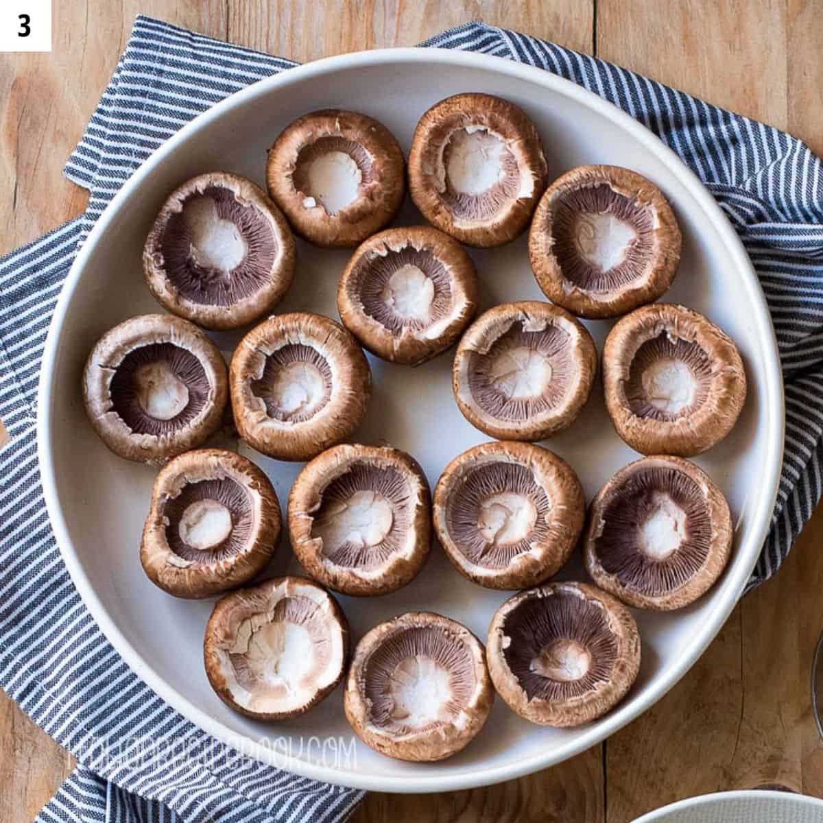 Mushroom caps on a plate ready for stuffing.