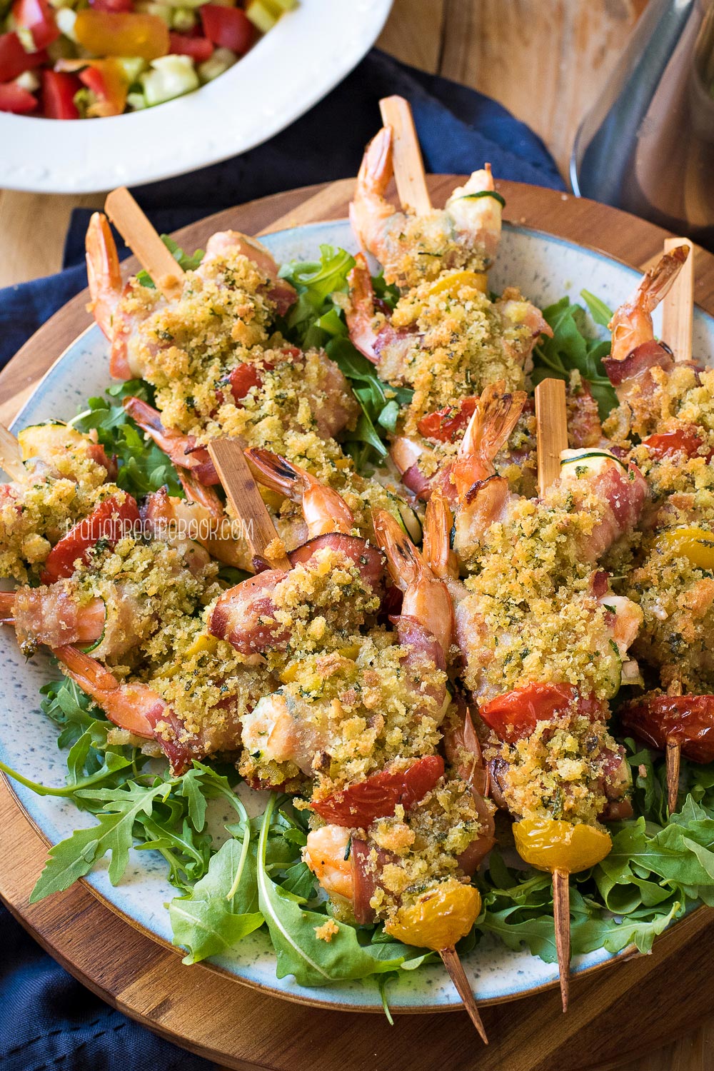 zucchini shrimp skewers on a plate on a bed of greens