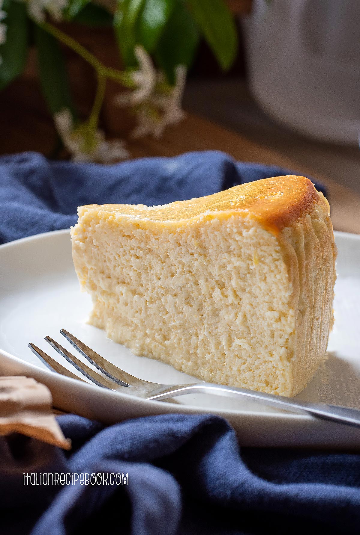 a piece of lemon ricotta cheesecake on a plate witha work on the side