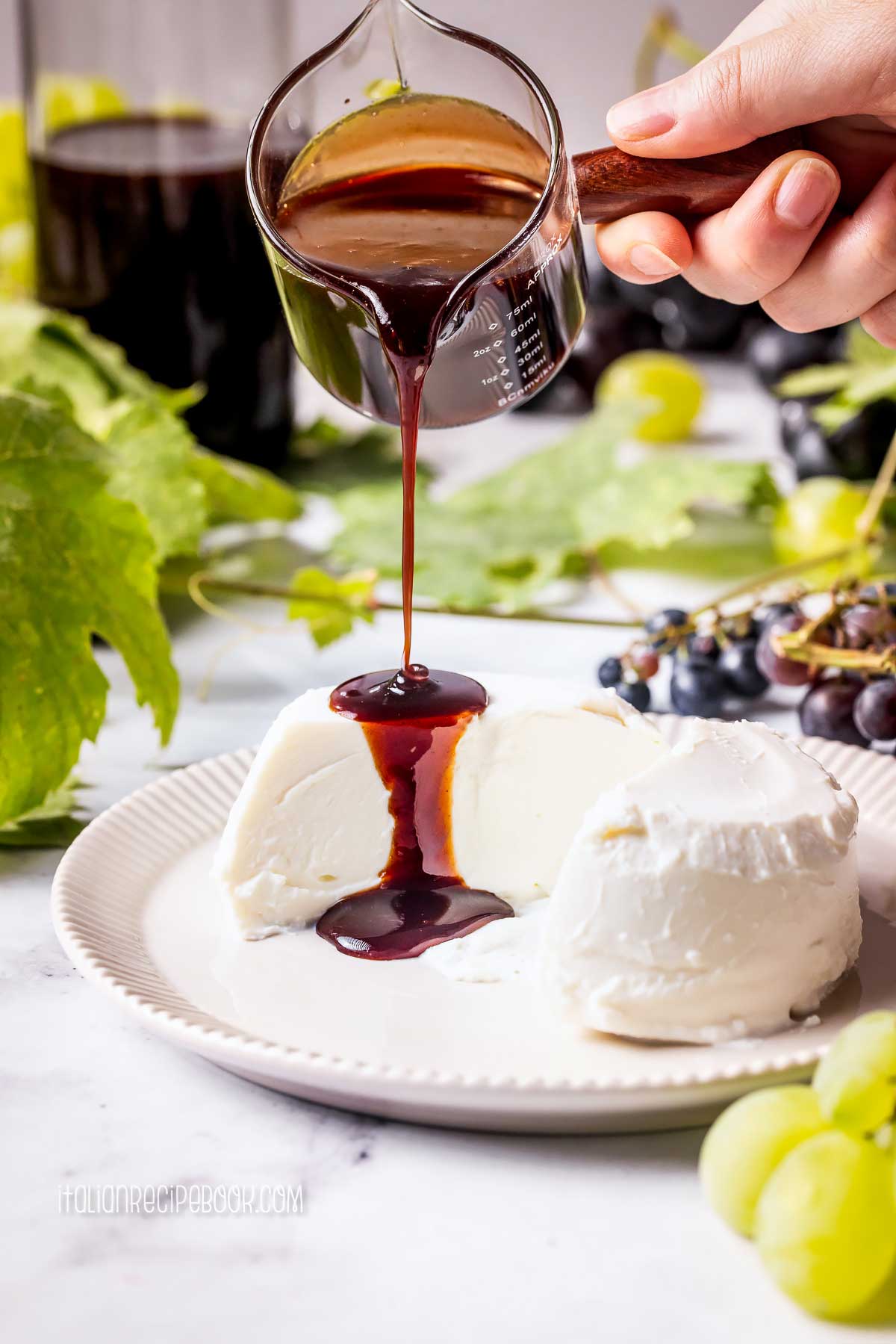 pouring freshly made vincotto on creamy ricotta cheese