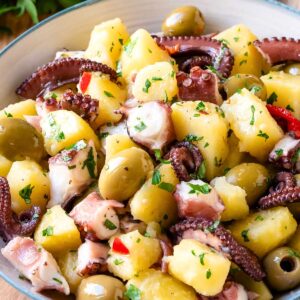 Octopus salad with potatoes and olives in a salad bowl.