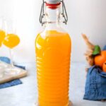 Arancello in a bottle with oranges in the background.