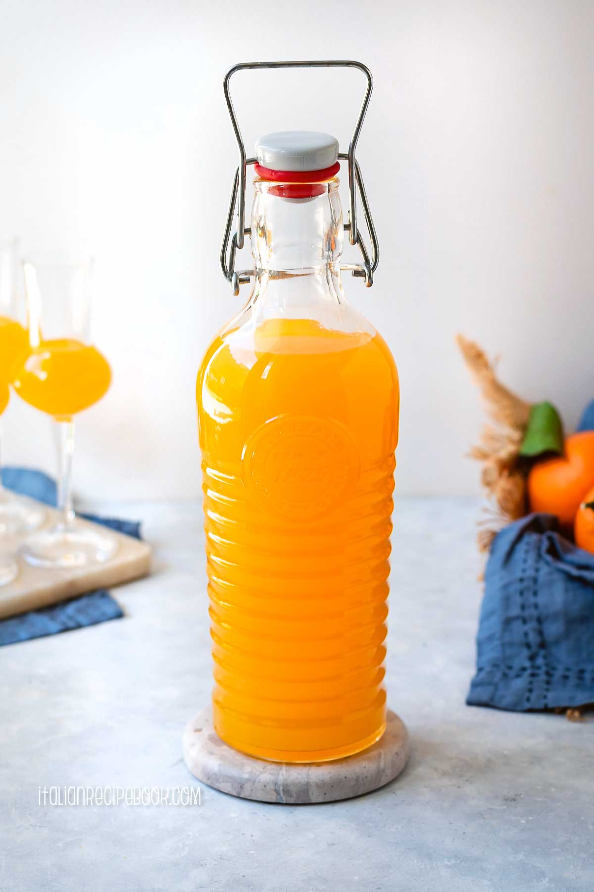 Arancello in a bottle with oranges in the background.