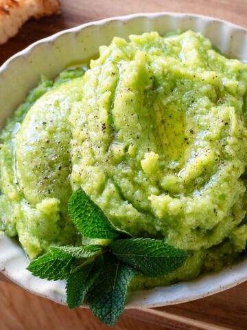 Fava bean pesto in a bowl garnished with mint leaves.