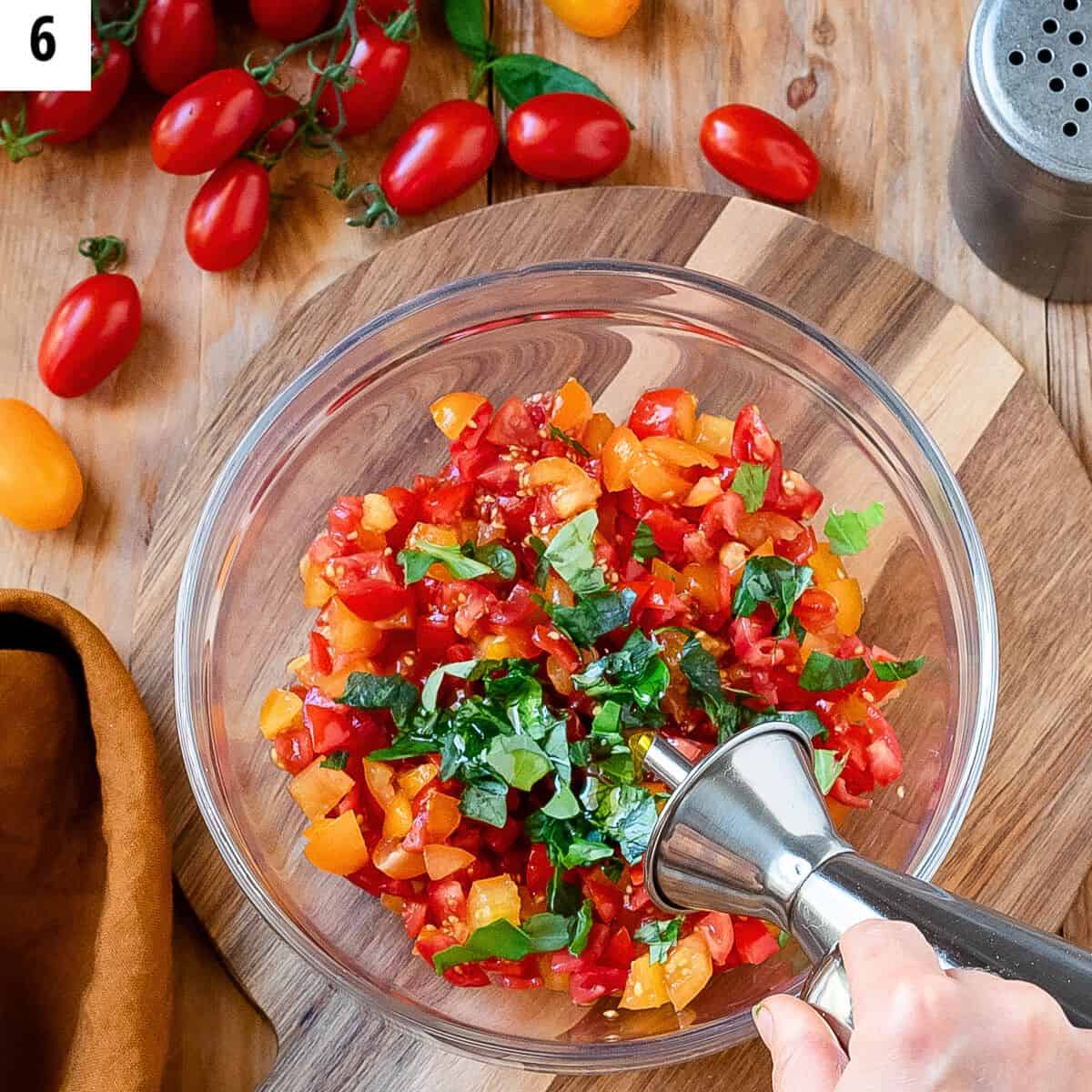 Adding extra virgin olive oil to a bowl with cherry tomatoes.