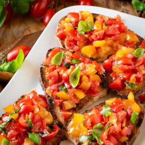 Cherry tomato bruschetta garnished with basil leaves.