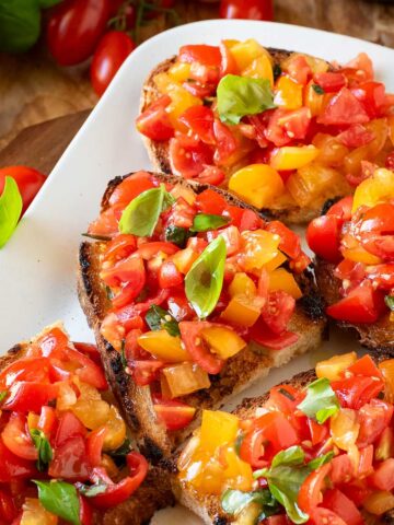 Cherry tomato bruschetta garnished with basil leaves.