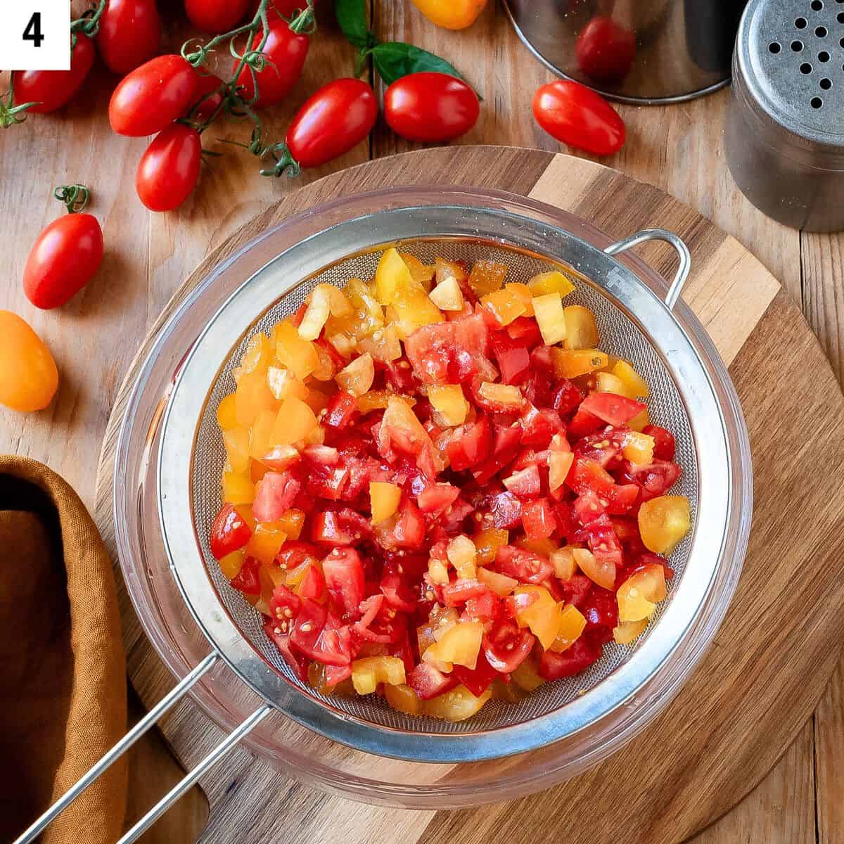 Diced cherry tomatoes placed in a sieve to drain excess liquid.