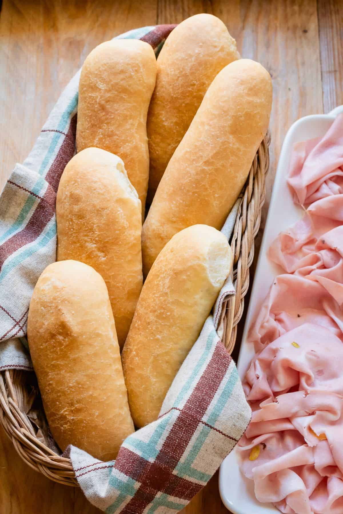 Freshly baked panini bread in a basket and sliced Mortadella on the side.