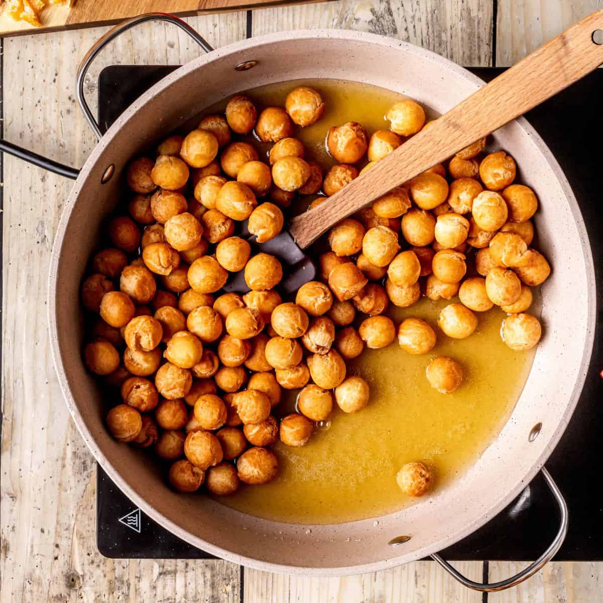 Coating fried struffoli with honey.