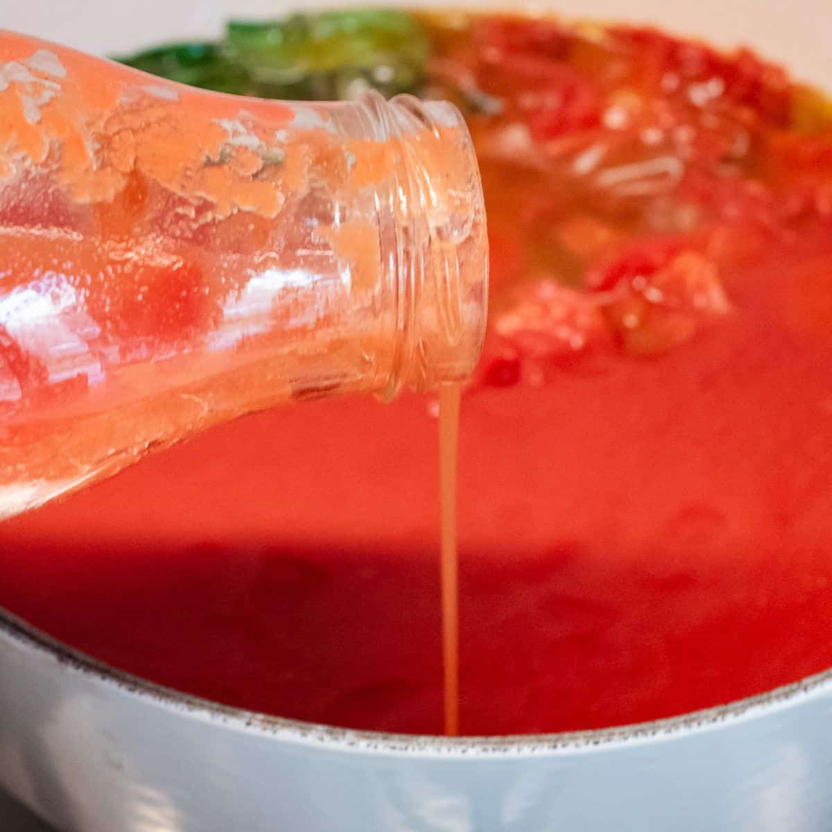 Rinsing tomato passata bottle with water to extra all tomato puree.