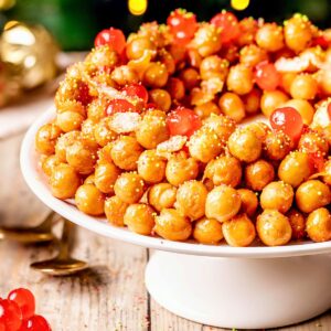 Struffoli honey balls on a white cake stand.