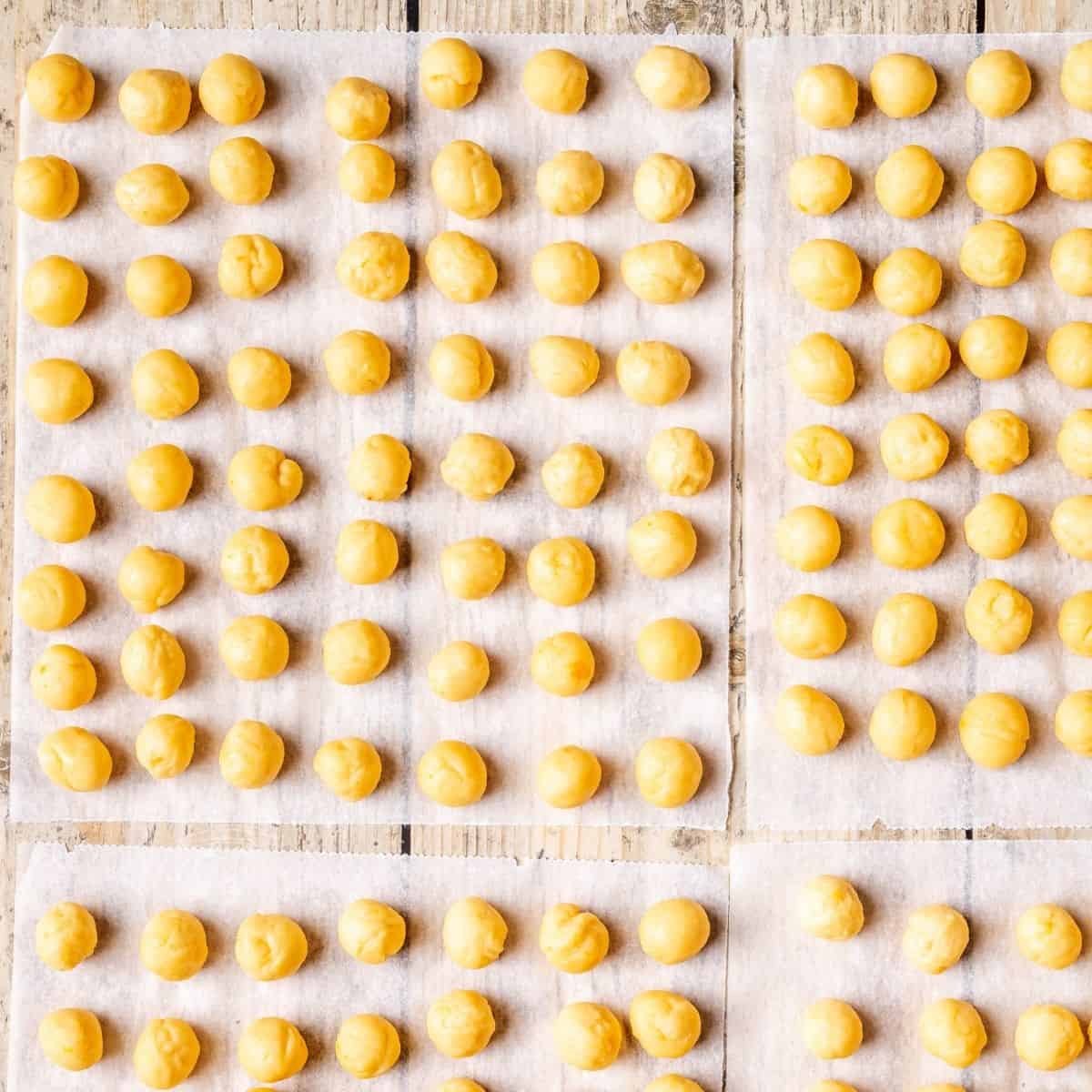 Struffoli balls arranges on parchment paper squares.