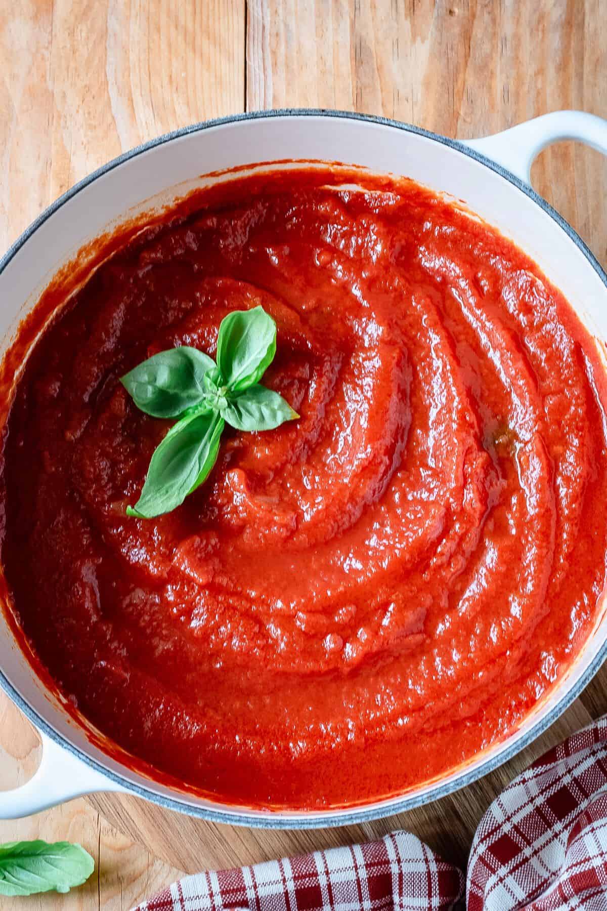 Italian tomato sauce in a pot garnished with fresh basil.