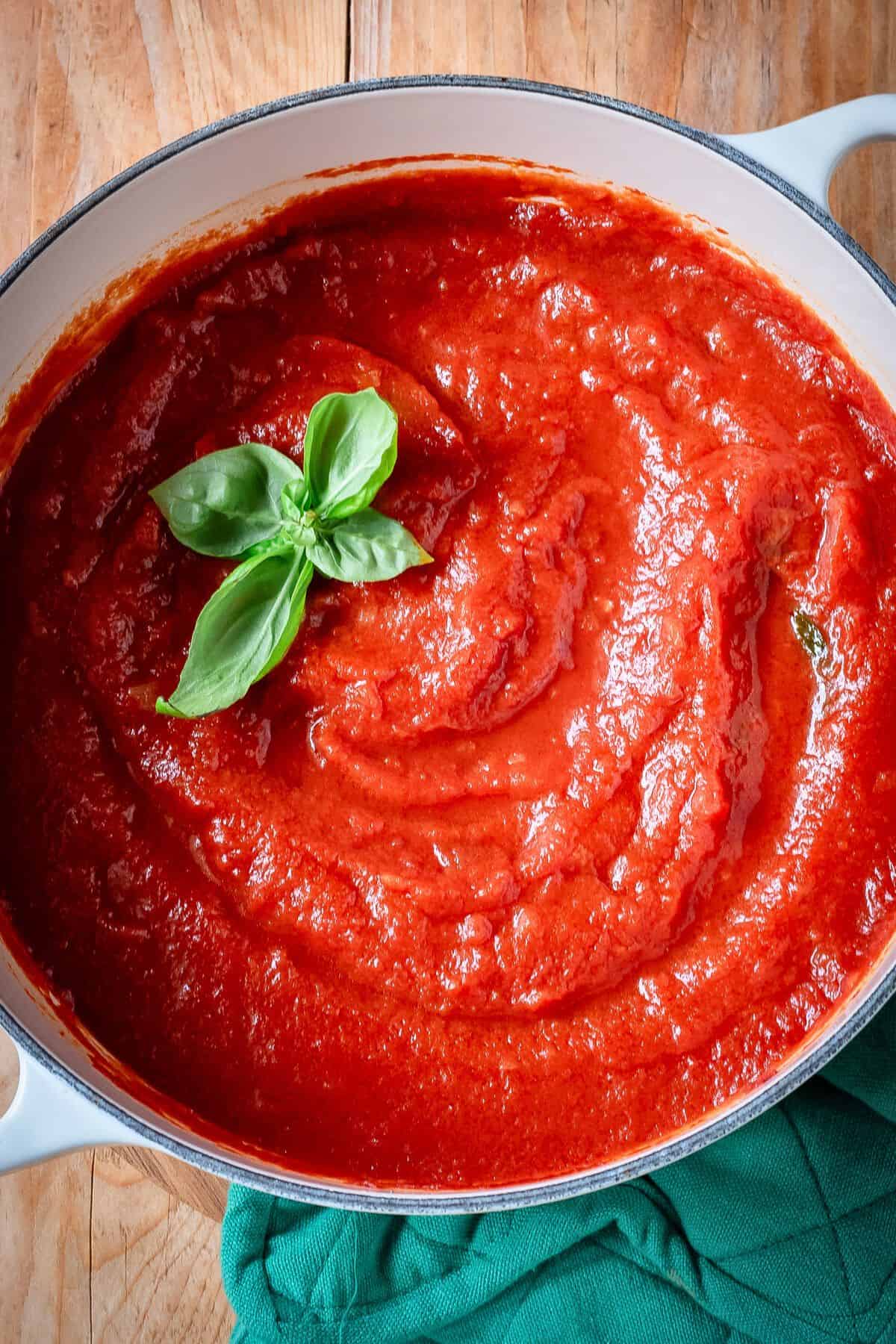 Sugo di pomodoro in a pot garnished with fresh basil.