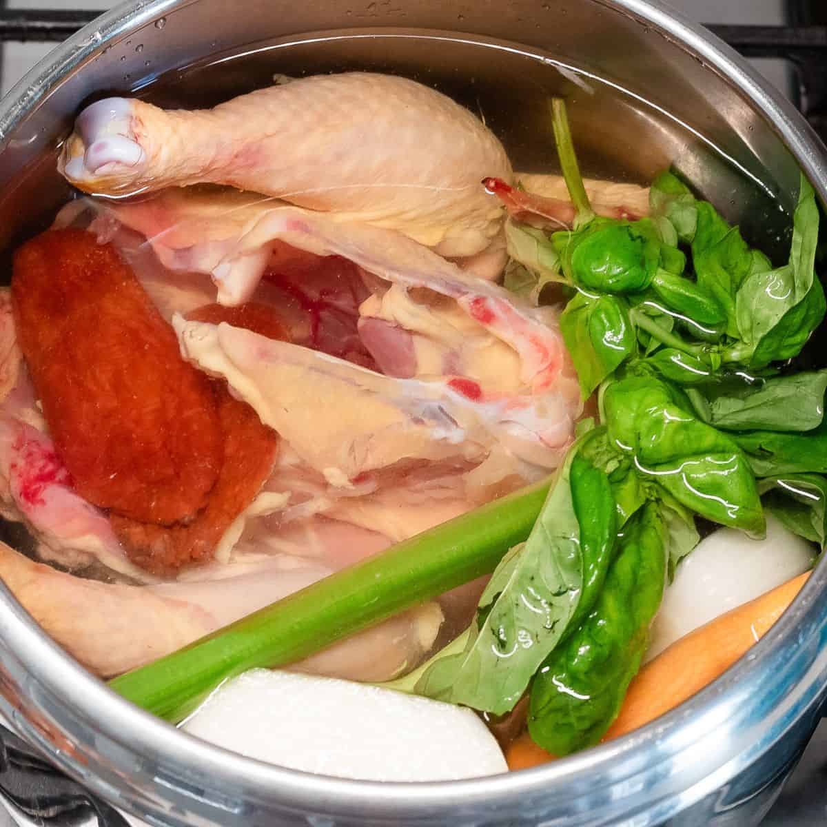 Broth ingredients in a pot covered with water.