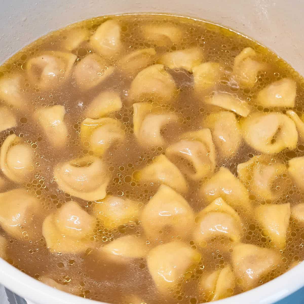 Cooking tortellini in broth.