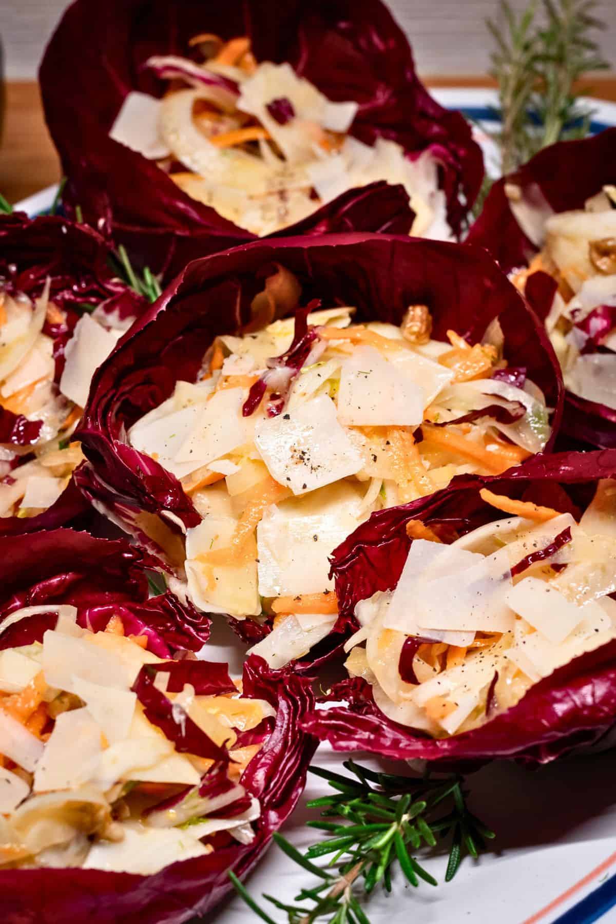 Radicchio salad cups on a tray garnished with fresh rosemary sprigs.