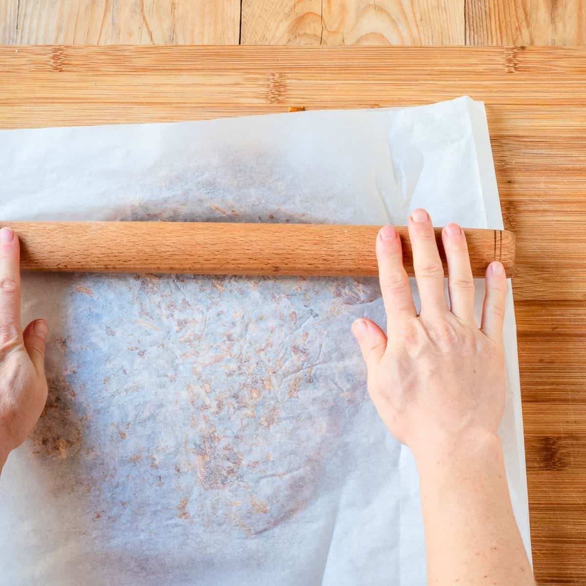 Rolling hot almond brittle with a rolling pin.