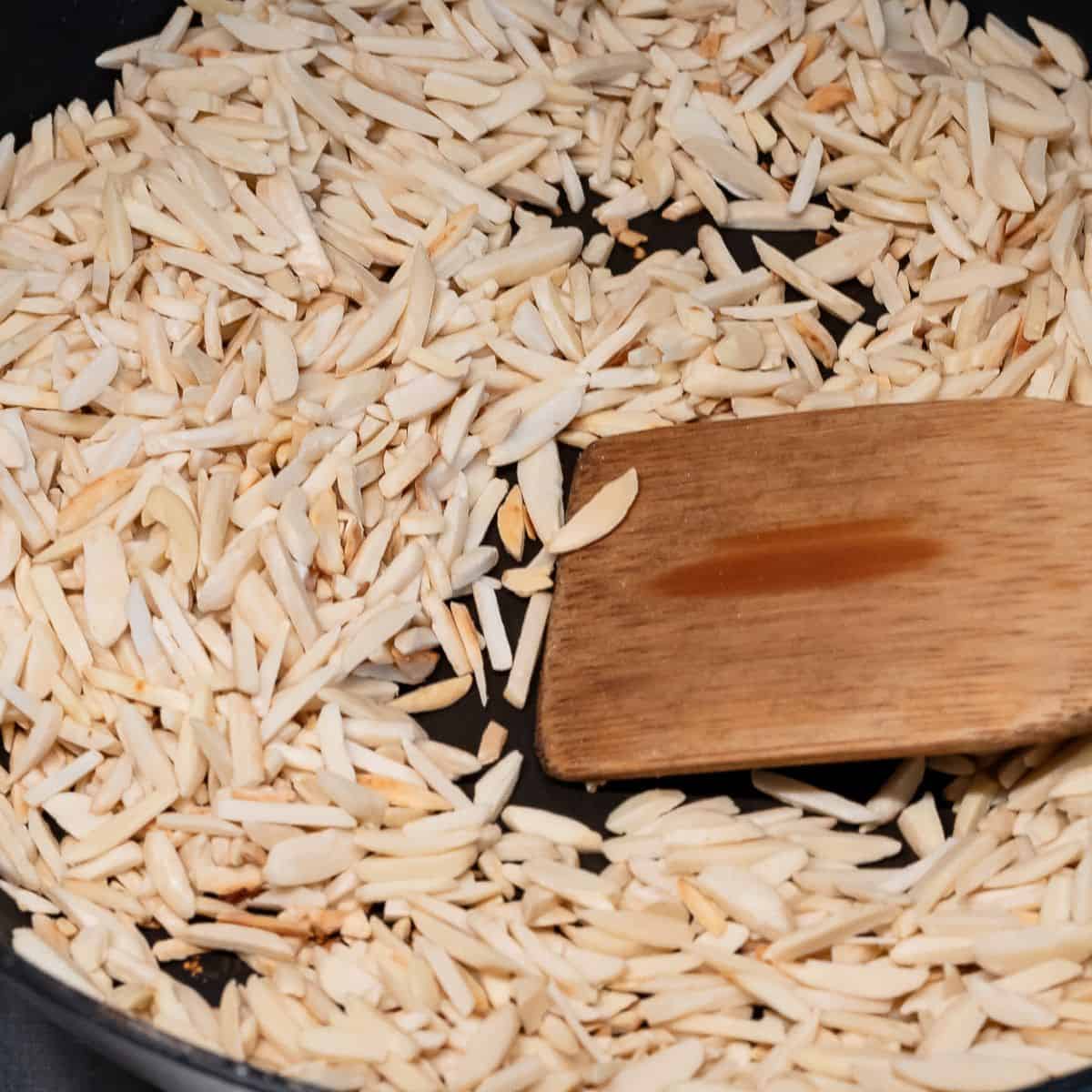 Toasting slivered almonds in a pan.