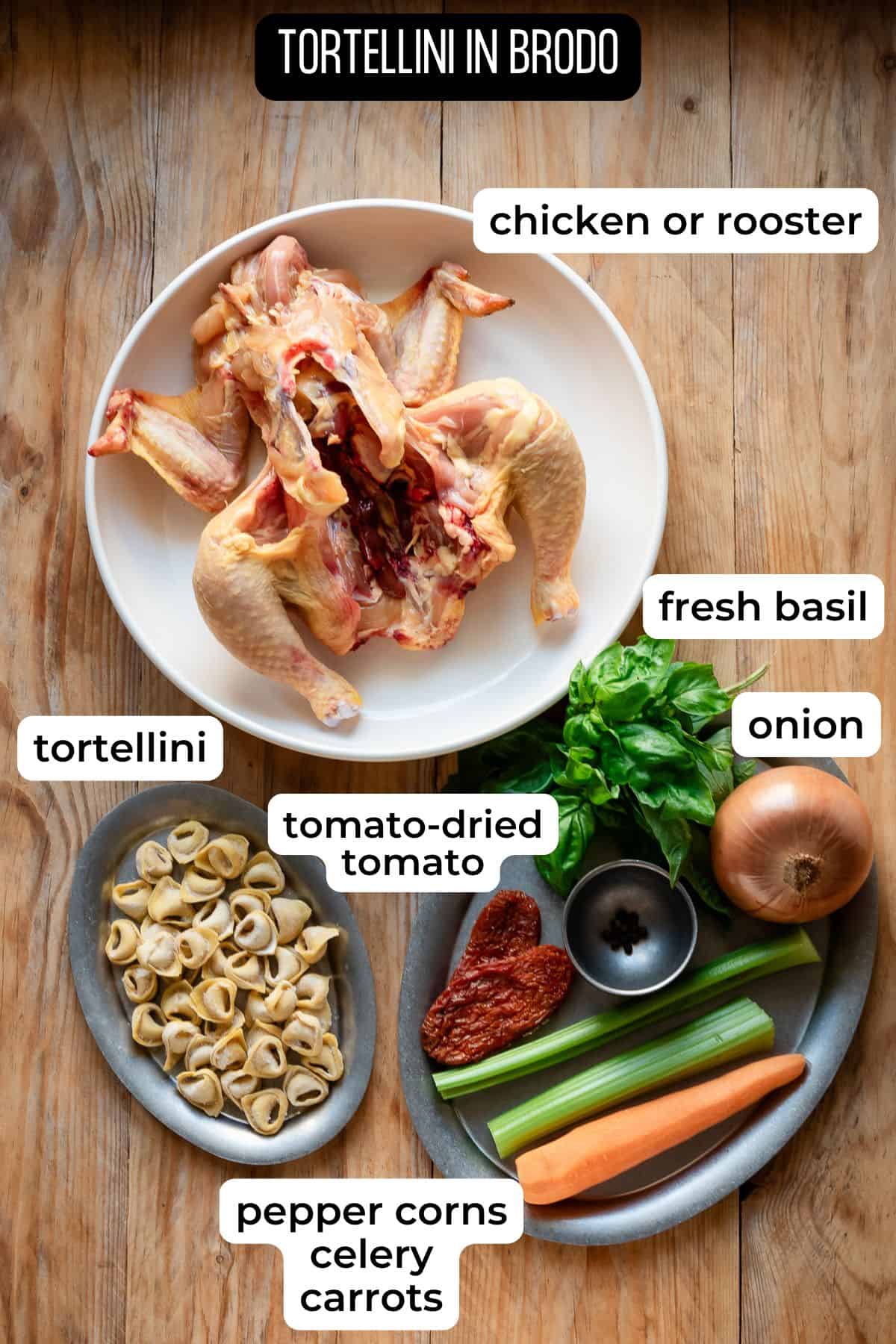 Ingredients needed to make tortellini in brodo laid on a wooden surface.