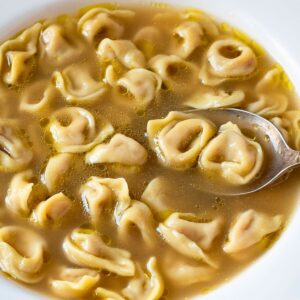 Tortellini in brodo in a plate with a spoon.