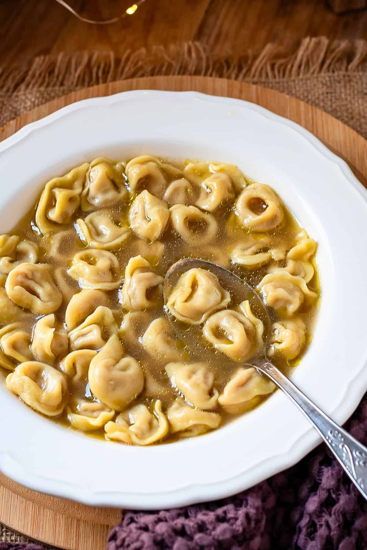 Tortellini in brodo in a bowl with a spoon.