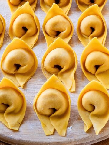 Cappellacci pasta on a wooden board.