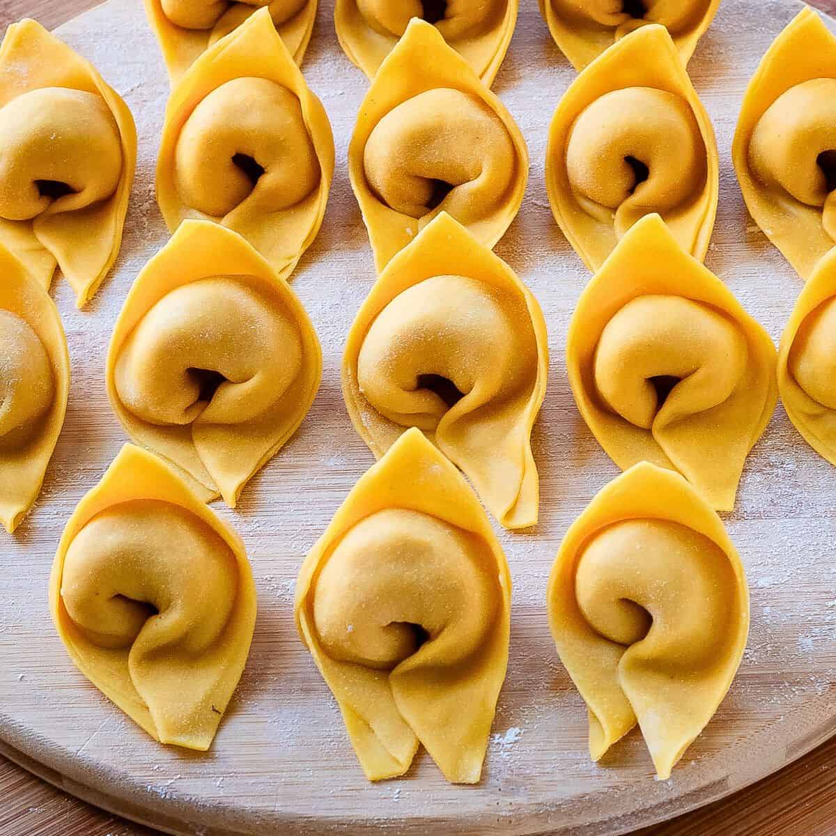 Cappellacci pasta on a wooden board.