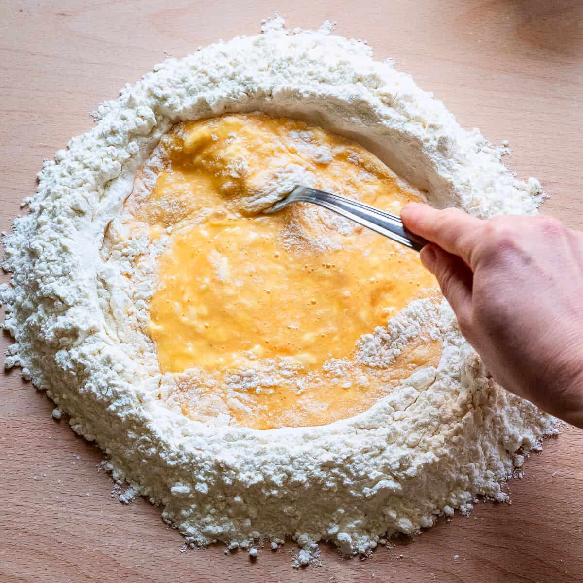 Beating eggs with a fork and incorporating flour.